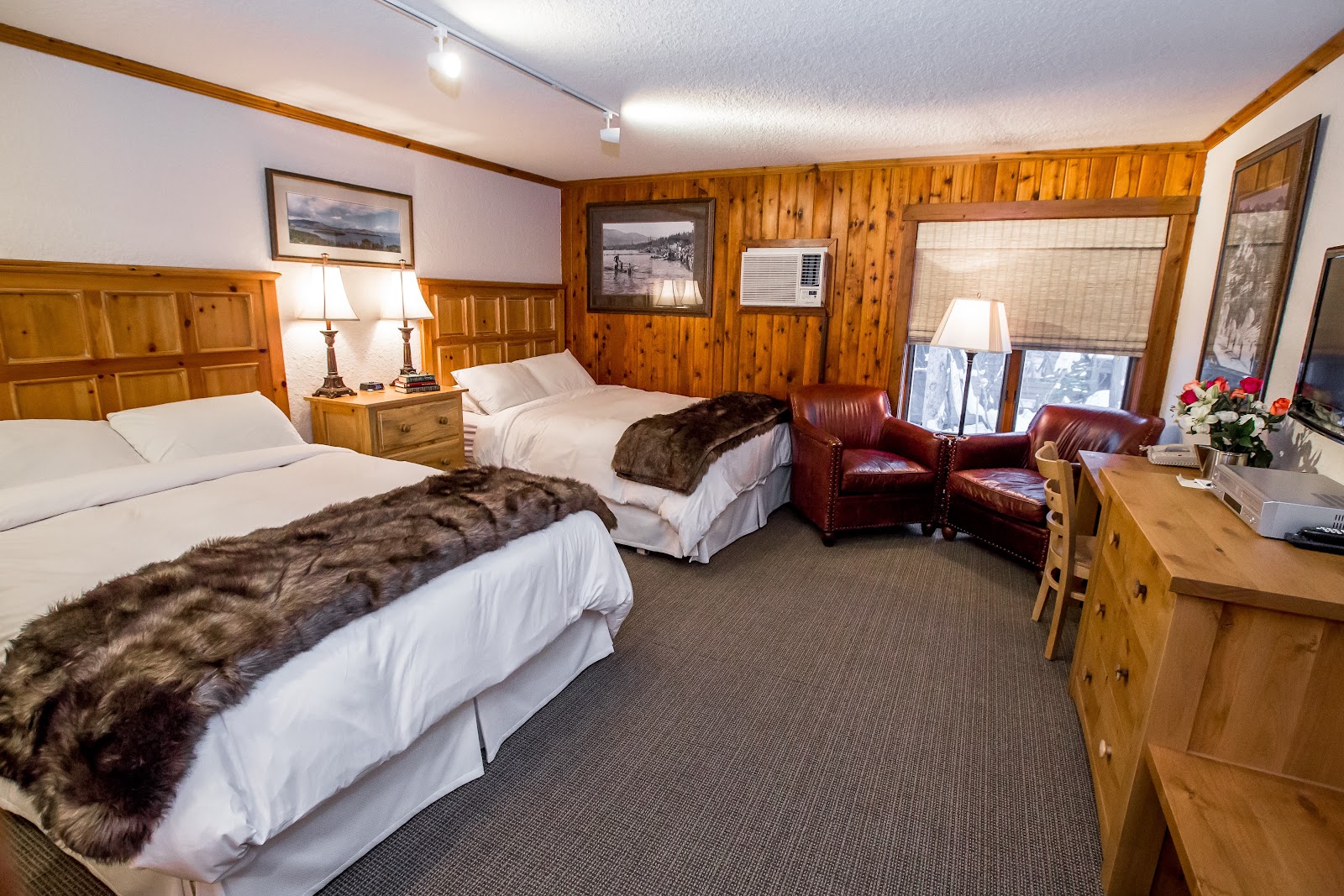 Window light falling off sharply across a dark timber lodge interior, Whitefish Montana