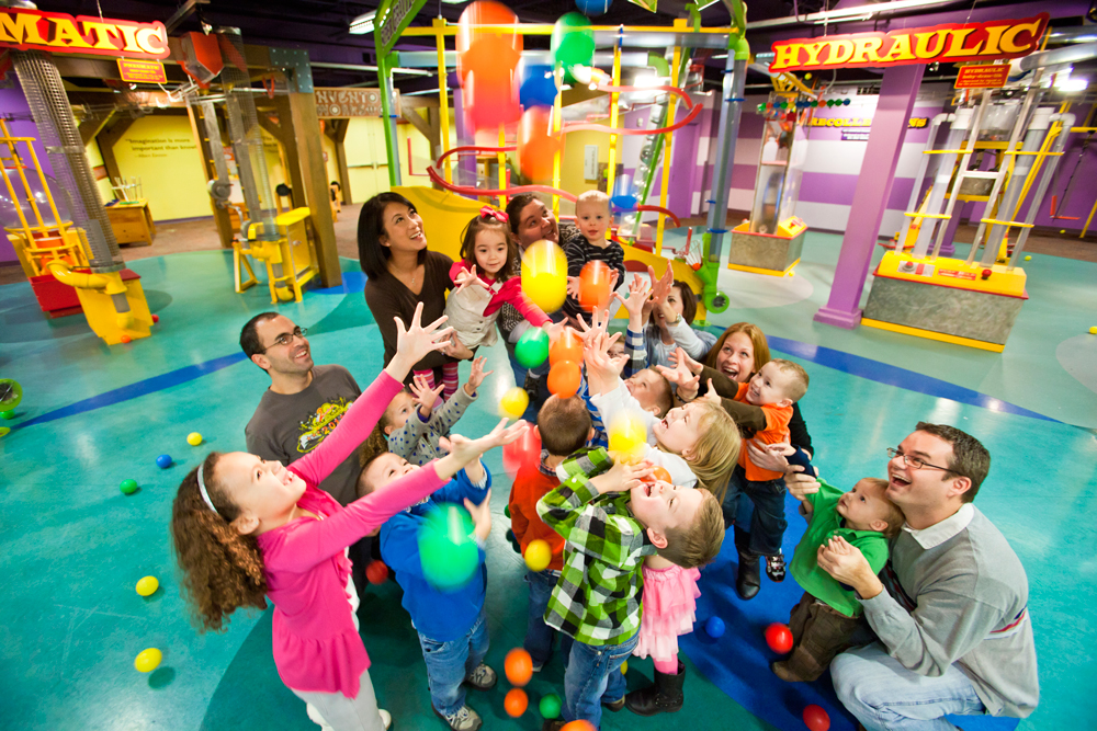 Interactive exhibit apparatus and signage cluttering a background at a children's museum