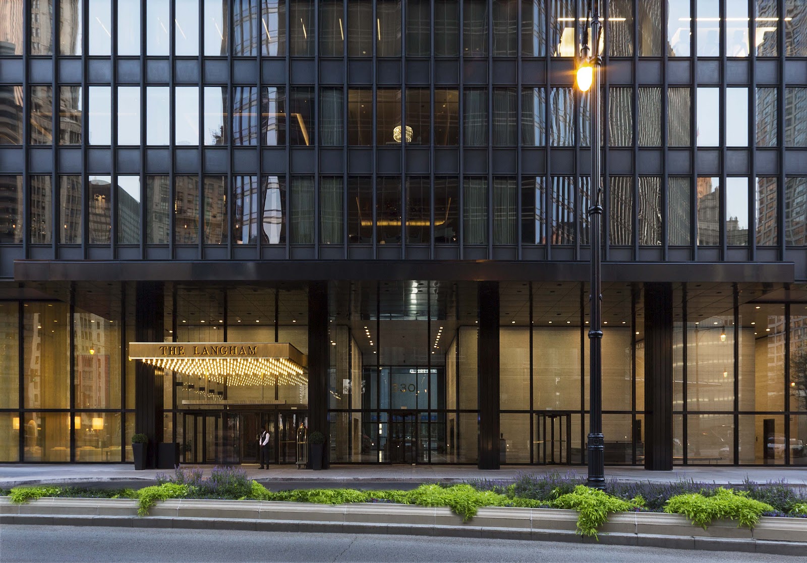 Couple placed precisely within the bay of a modernist steel and glass facade